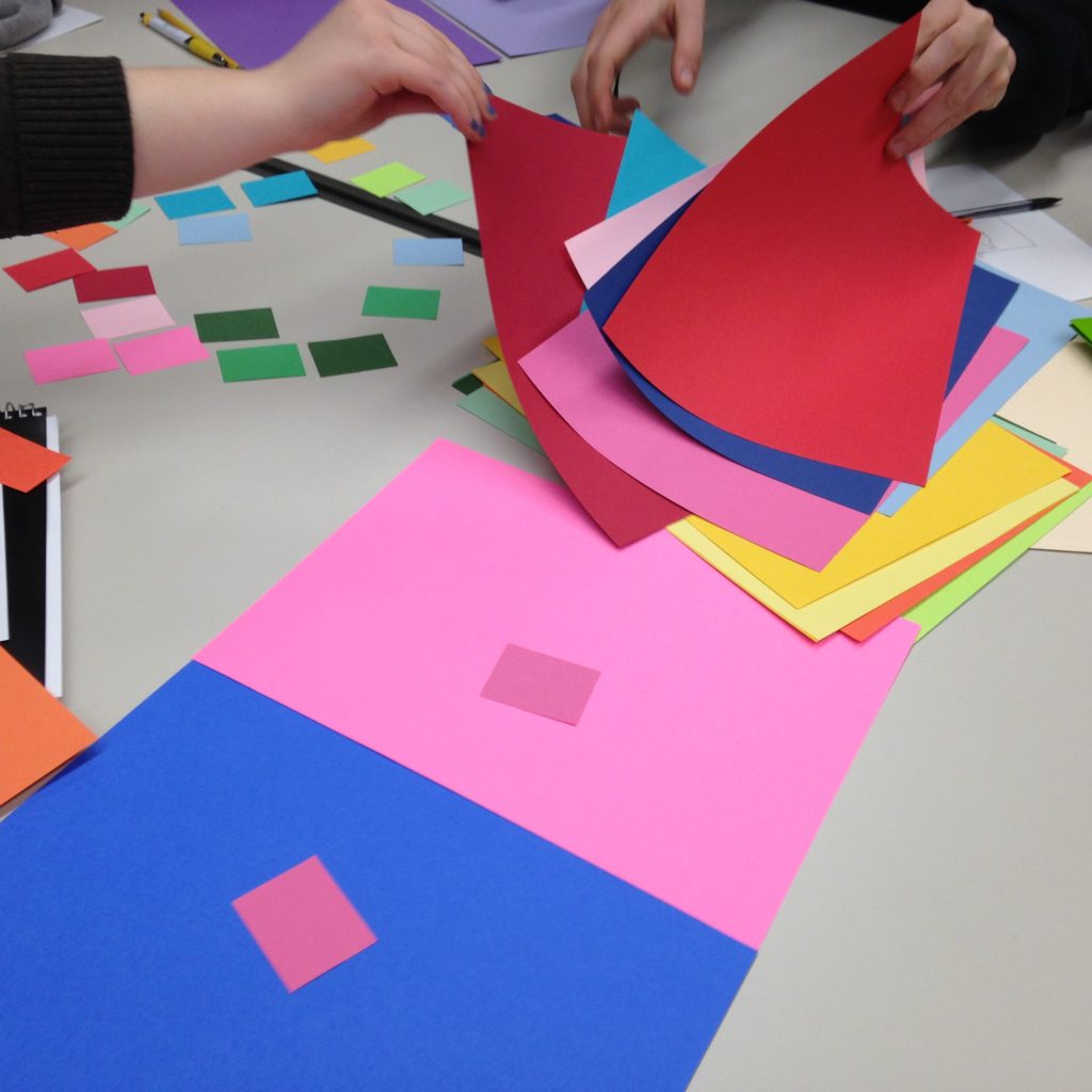 Students experimenting with sheets of paper of various colors.