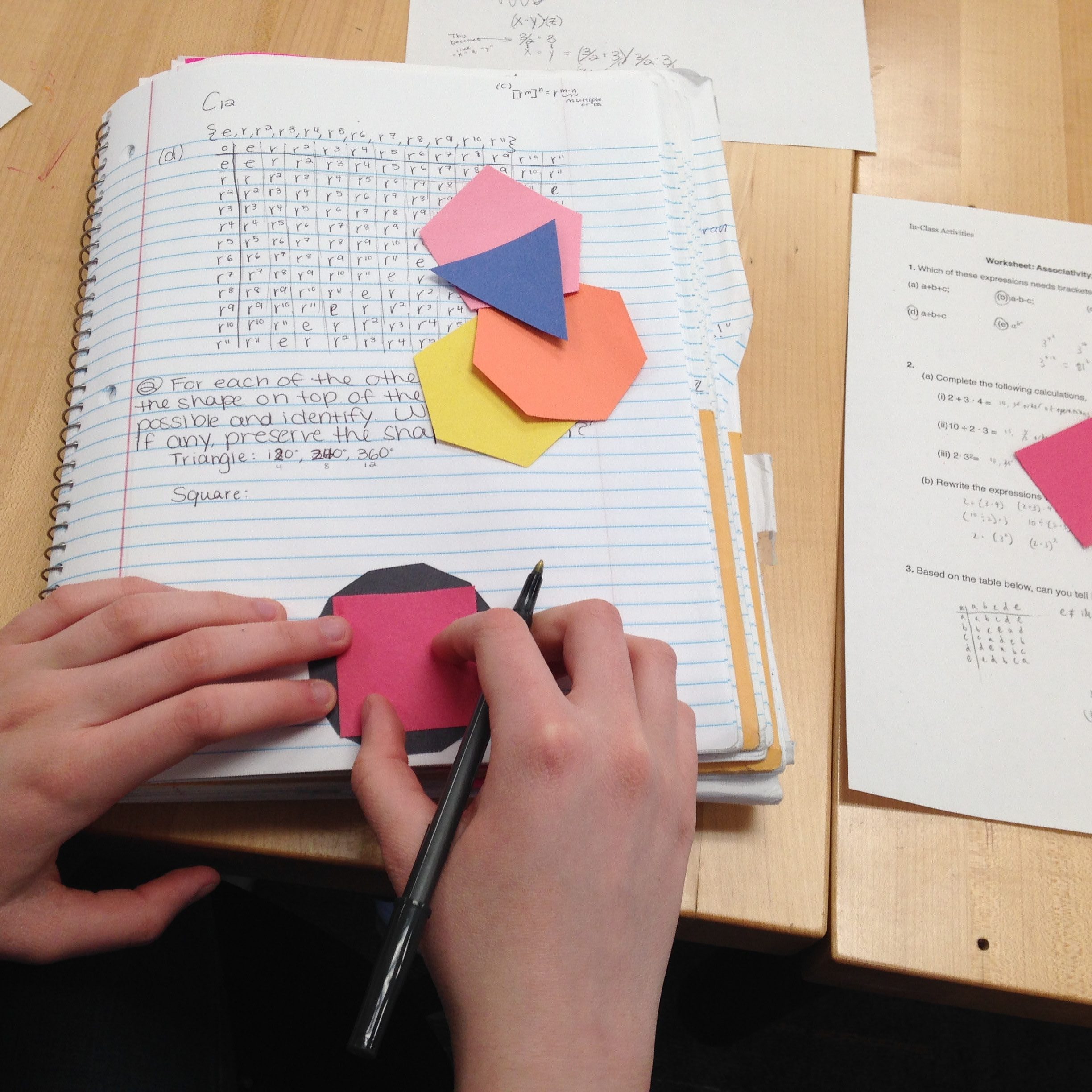 Hands of a student playing with cut outs of regular polygons. 